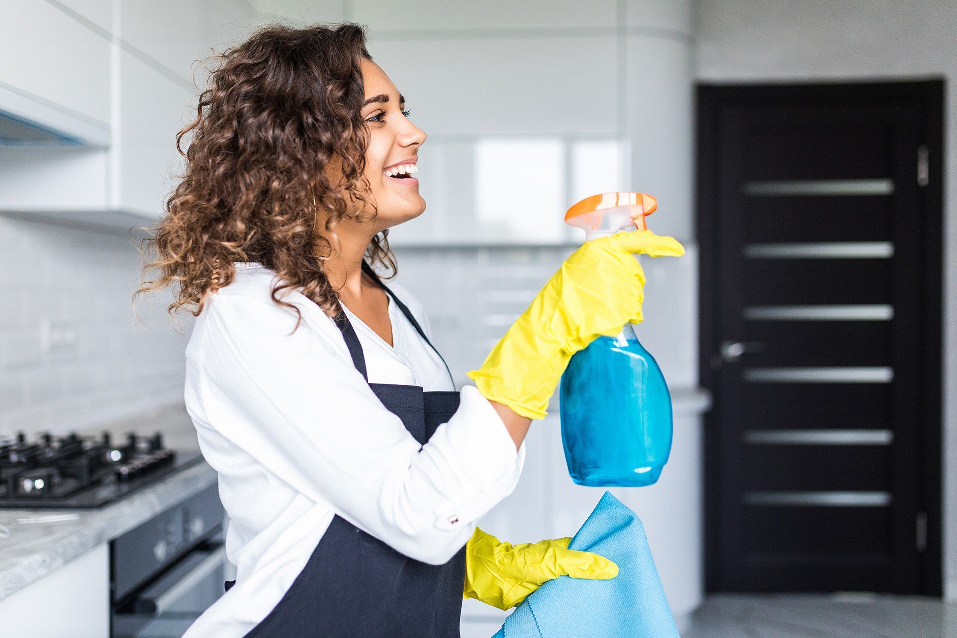 Werkster maakt lachend de keuken schoon